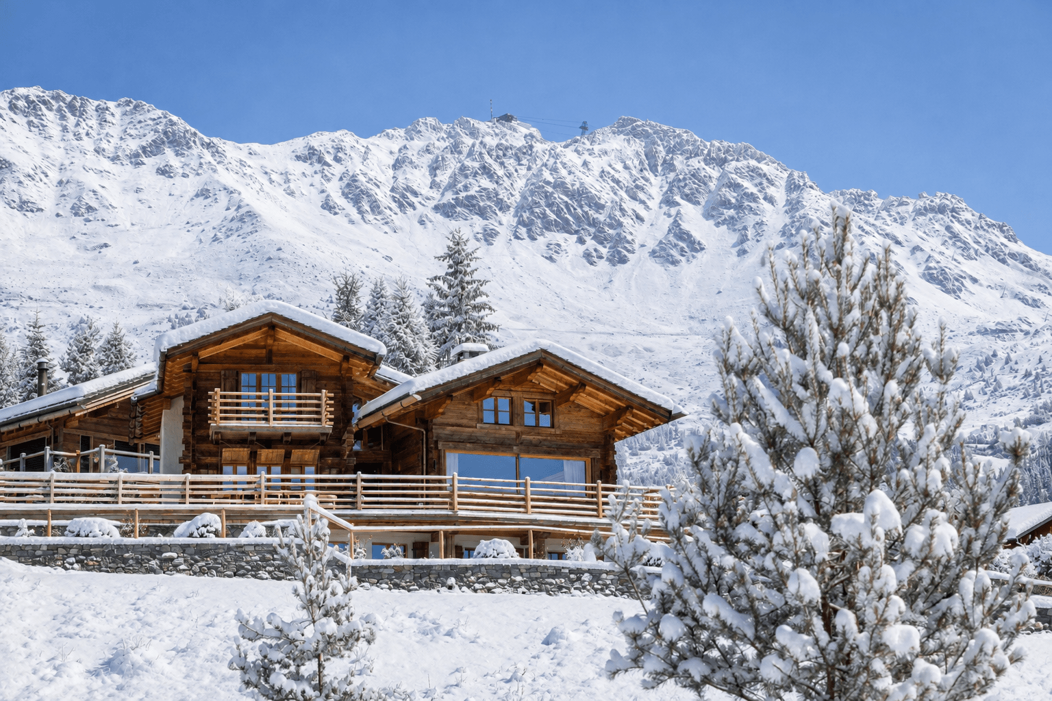 Sun drenched terrace with dining table looking out over snow covered mountains at Chalet les Etoiles d'Amon